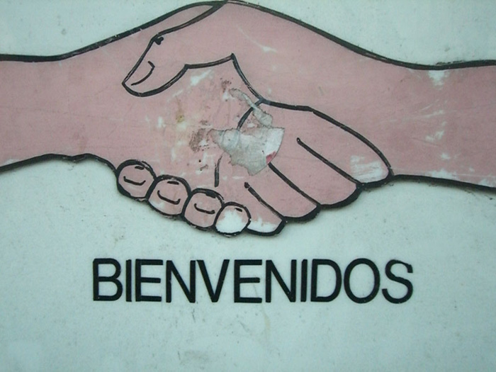 An illustration of two shaking hands over the word Bienvenidos