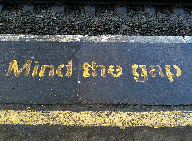 Painted before train tracks are the words "Mind the Gap"