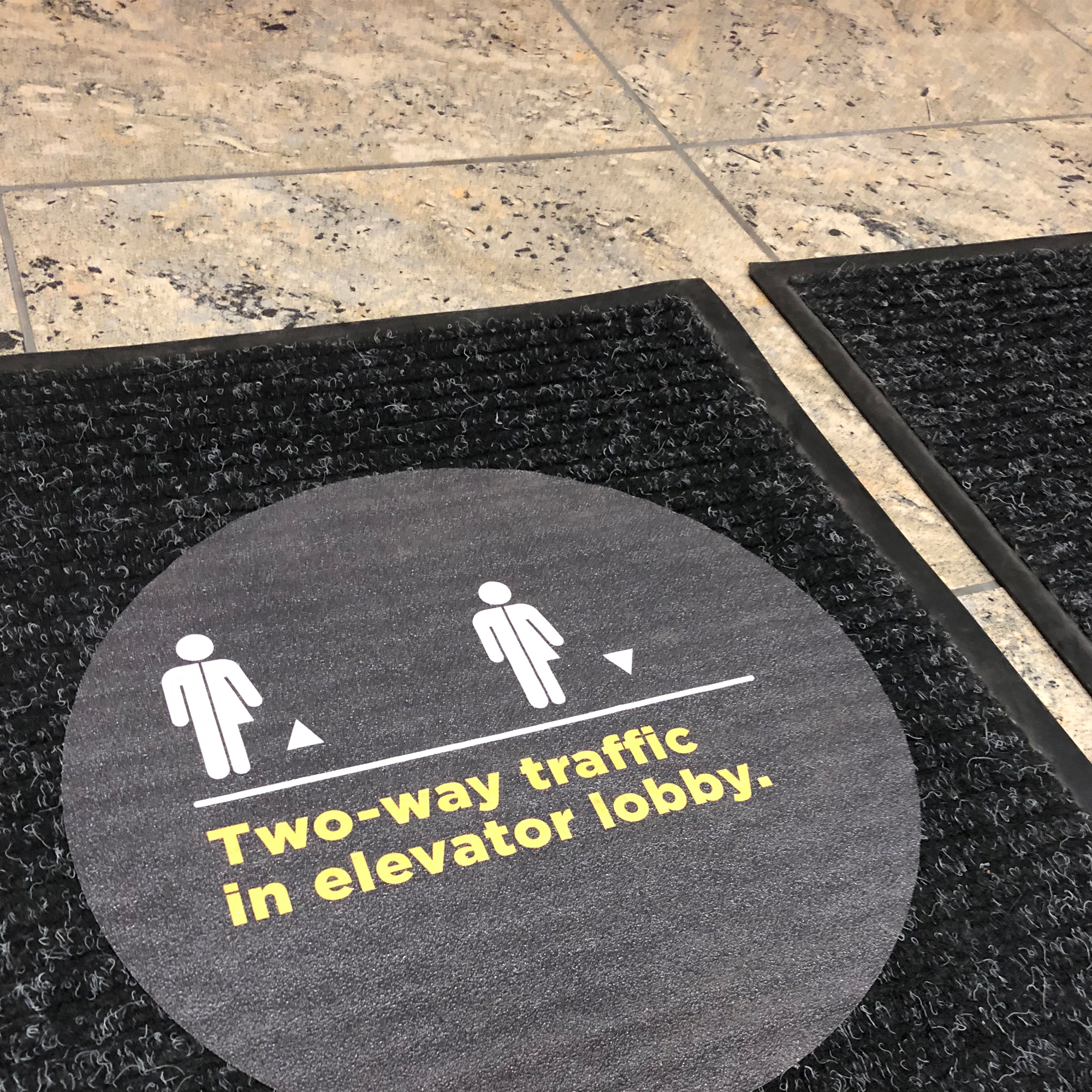 Wayfinding signage floor decal that reads "two-way traffic in elevator lobby"