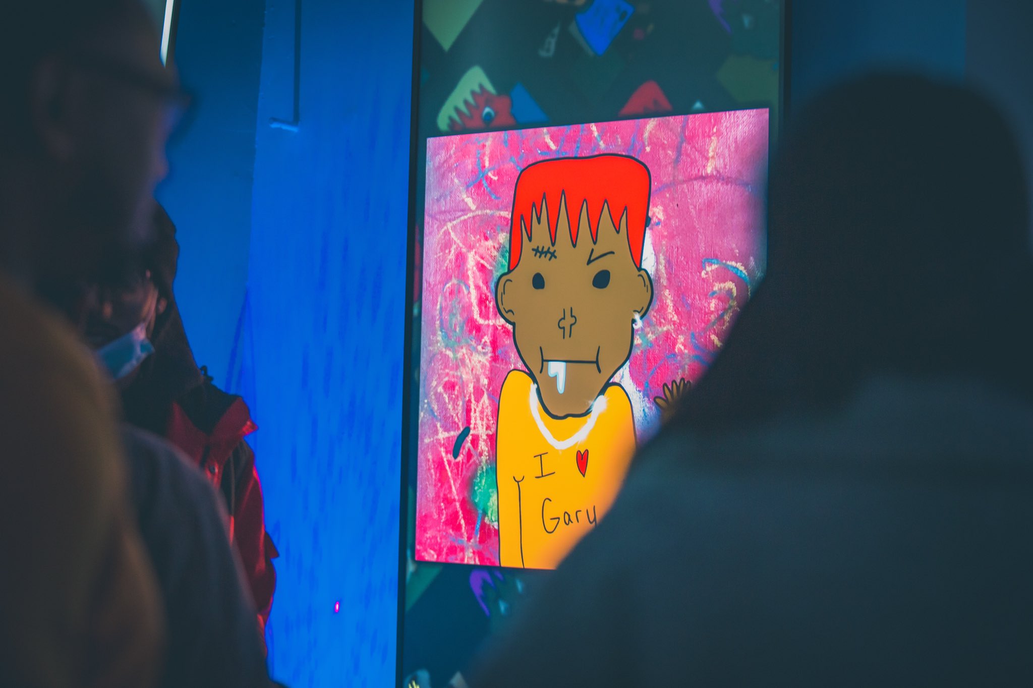 People looking at a digital illustration of a person with red hair, light brown skin wearing a yellow shirt that reads I <3 Gary
